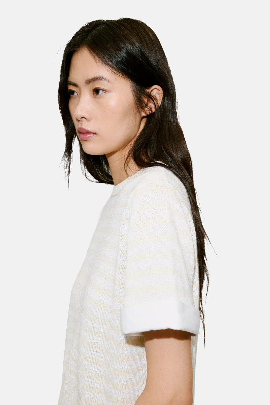 Ecru short-sleeve knit top with soft ribbed texture and rolled cuffs, side view on model