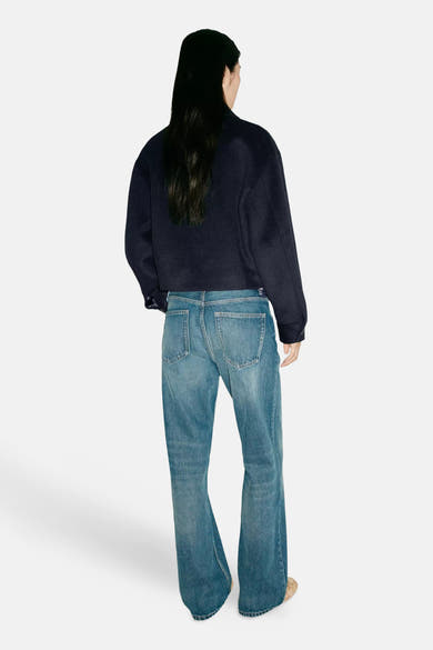 Veste bleu marine ample vue dos par MANGO, portée avec jeans délavés et bottines claires