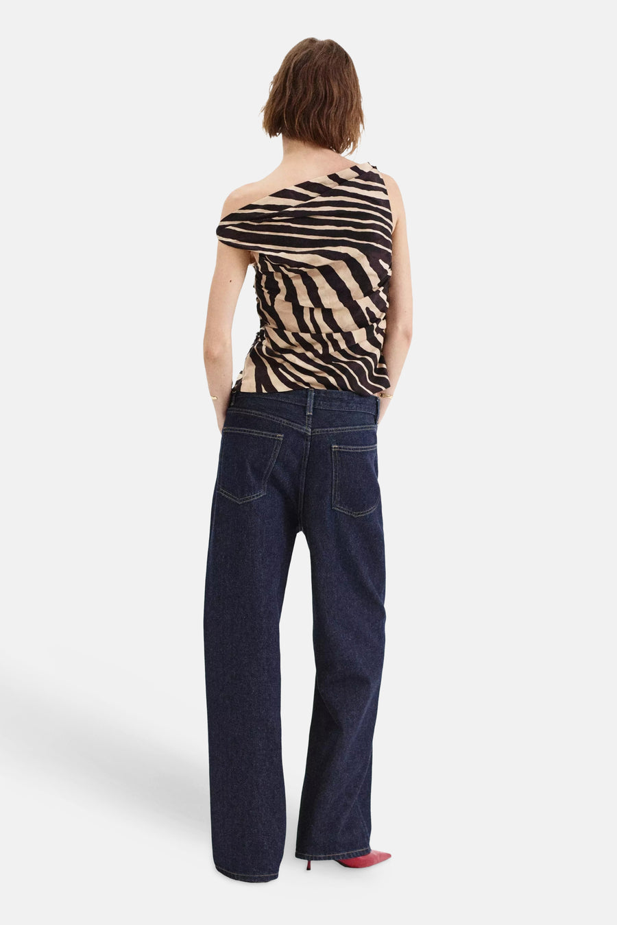 Multicolored sleeveless blouse with black and beige zebra print, back view, worn with dark denim pants and red heels