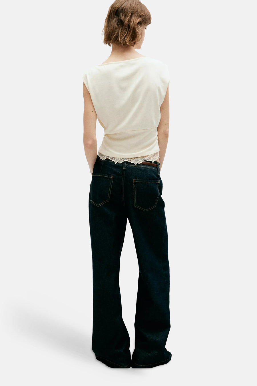 Écru sleeveless top with lace hem, back view, worn with dark denim jeans