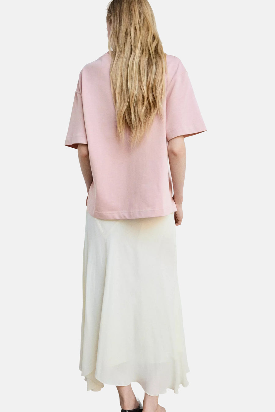 Rose short-sleeve t-shirt with relaxed fit, back view, worn with flowing cream skirt and black sandals