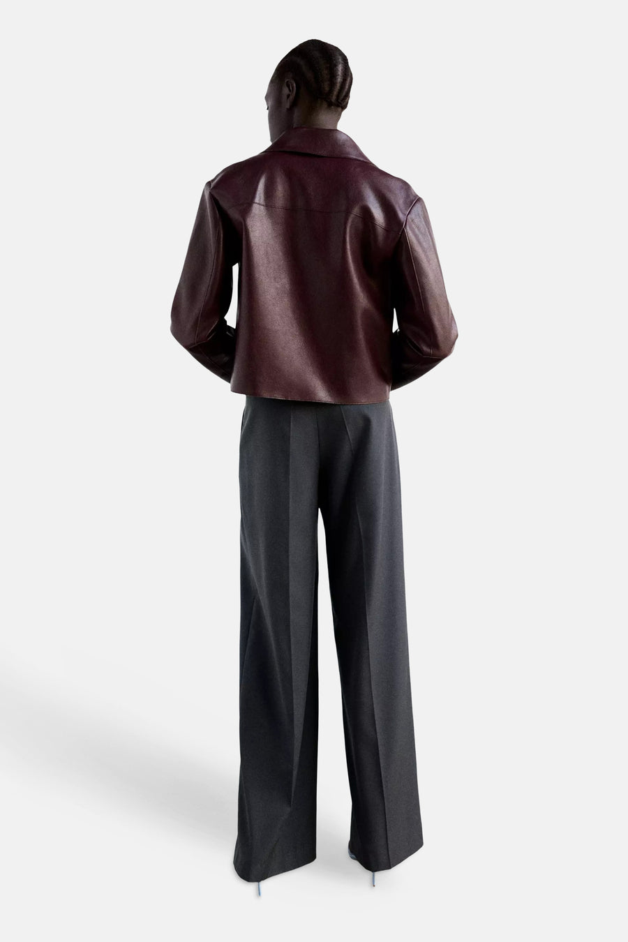 Bordeaux leather jacket back view with structured shoulders and slim fit, worn with dark wide-leg trousers