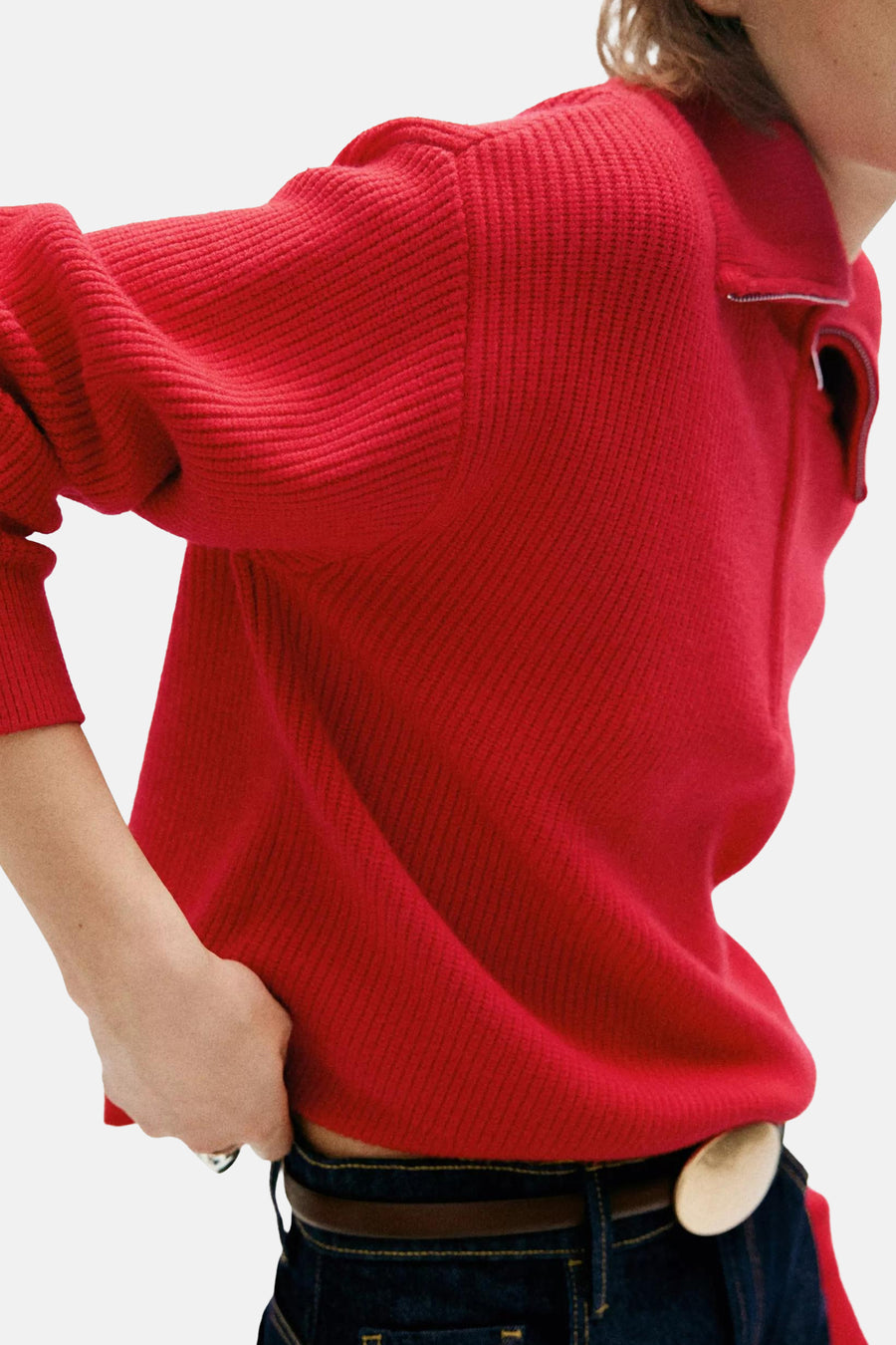 Pull rouge col montant à texture côtelée par MANGO, vue de profil avec jeans et ceinture marron