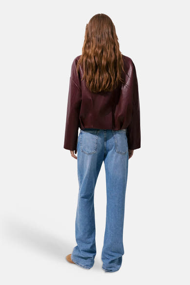 Bordeaux leather bomber jacket back view with relaxed fit, worn with light blue flared jeans and brown shoes