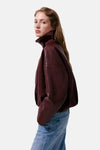 Bordeaux leather bomber jacket with high collar and relaxed fit, side view on model wearing blue jeans