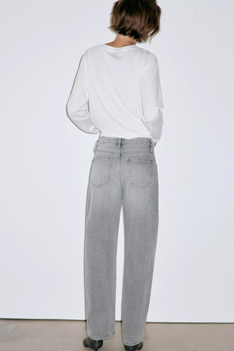 Jeans gris moyen à coupe large par MANGO, vue arrière, avec poches carrées et ourlet droit, portés avec un haut blanc.
