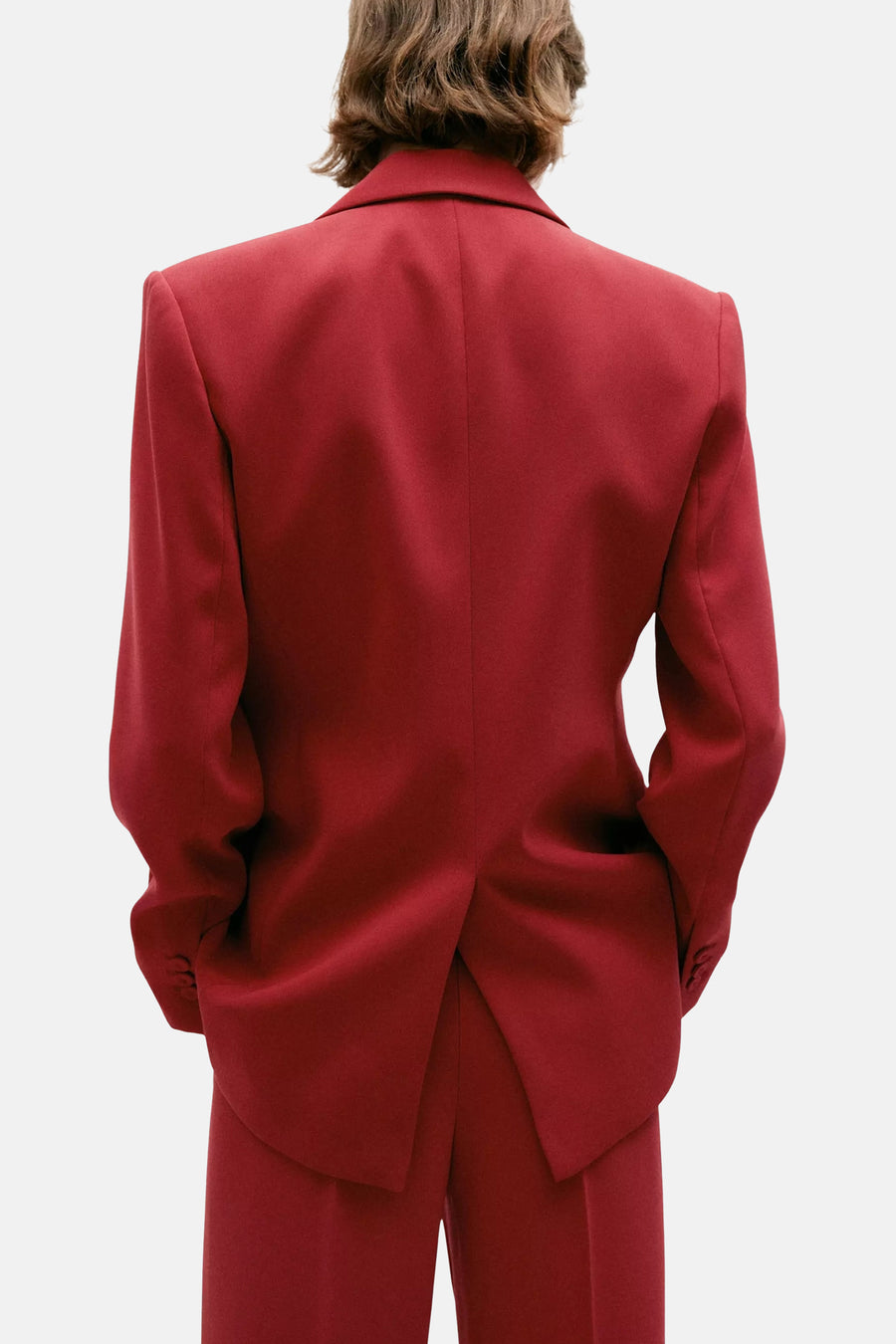 Red blazer with structured shoulders and single back vent, back view, worn with matching trousers
