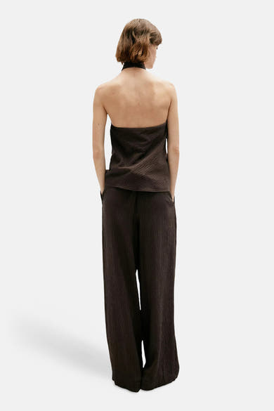 Brown textured wide-leg chinos from back view, featuring ribbed fabric and relaxed fit, worn with matching strapless top.