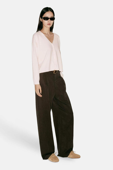 Cardigan rose à col en V de MANGO, porté avec un pantalon large marron et des lunettes de soleil, vue de profil.