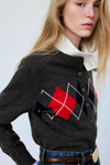Gilet multicolore en tricot gris à motif losange rouge et noir par MANGO, porté sur chemise blanche, vue de profil