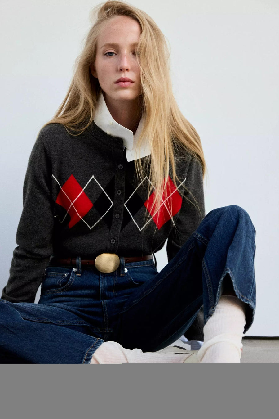 Gilet multicolore à motif losange par MANGO, en tricot gris avec détails rouges et noirs, porté sur chemise blanche, vue lifestyle
