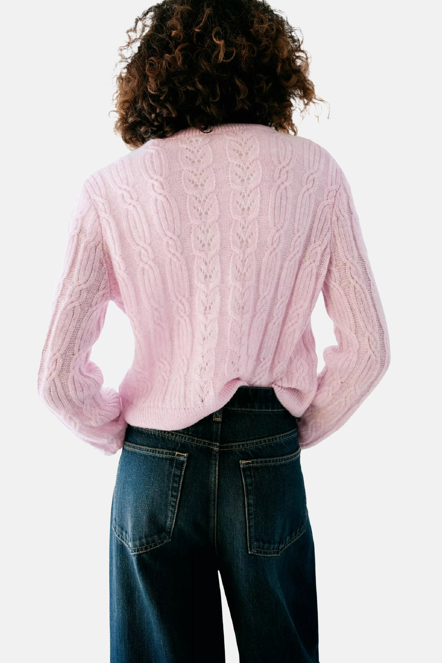 Gilet rose en tricot côtelé par MANGO, vue arrière avec motif torsadé et détails ajourés, porté avec un jean bleu foncé