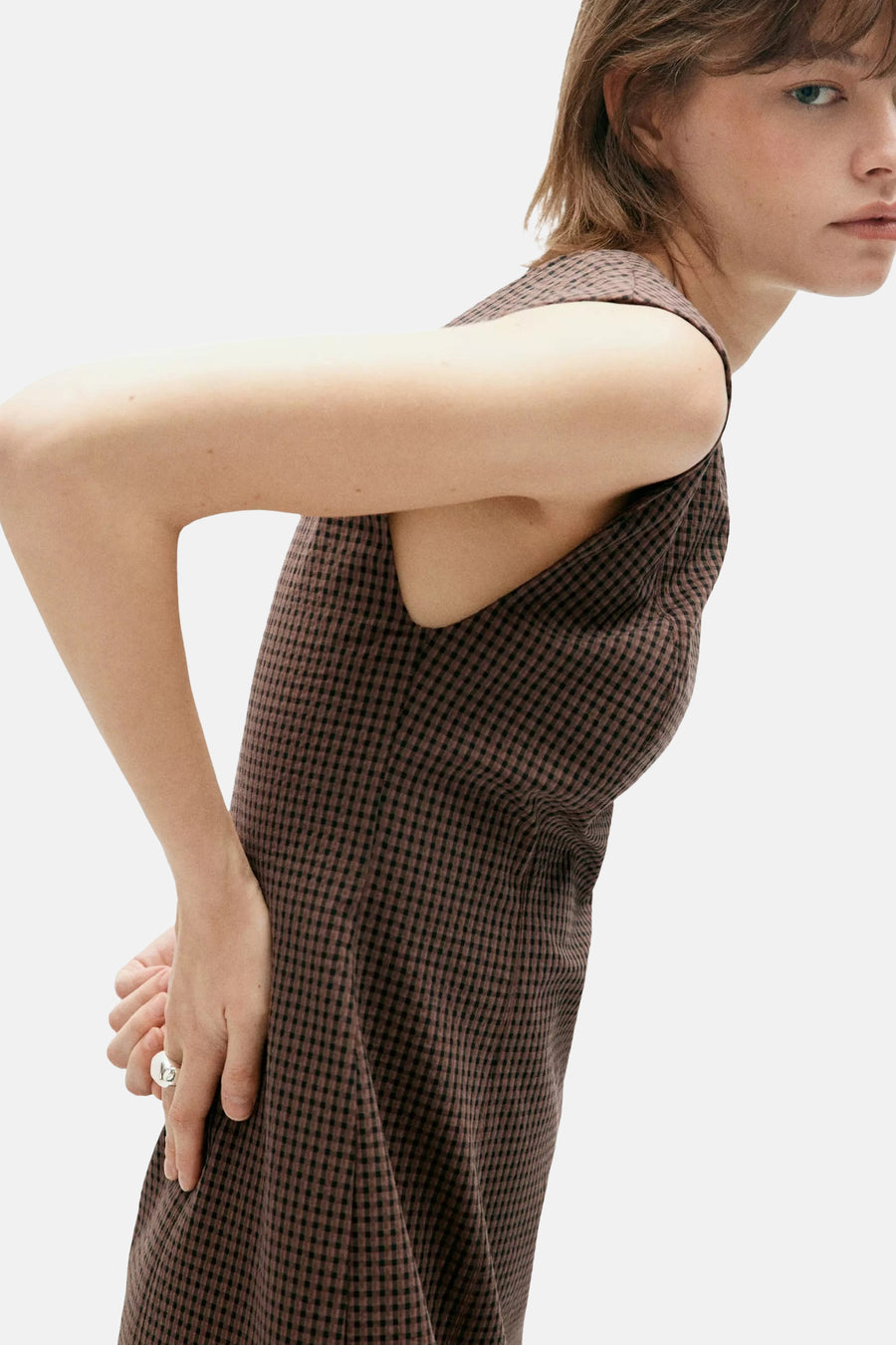 Multicolored sleeveless dress with brown and black checkered pattern, side view showing relaxed fit and textured fabric