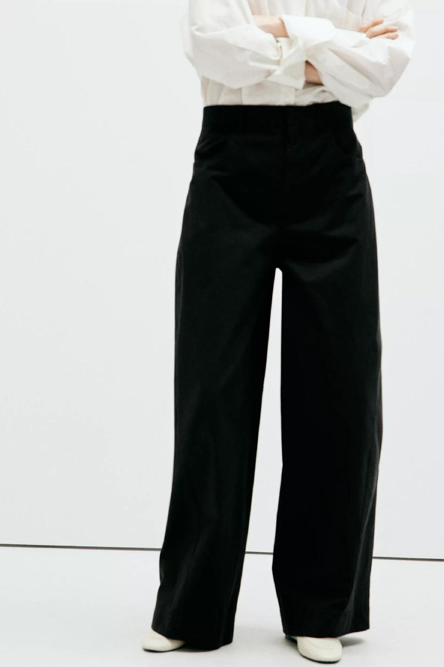 Pantalon cargo noir ample par MANGO, vue de face, porté avec chemise blanche et chaussures claires