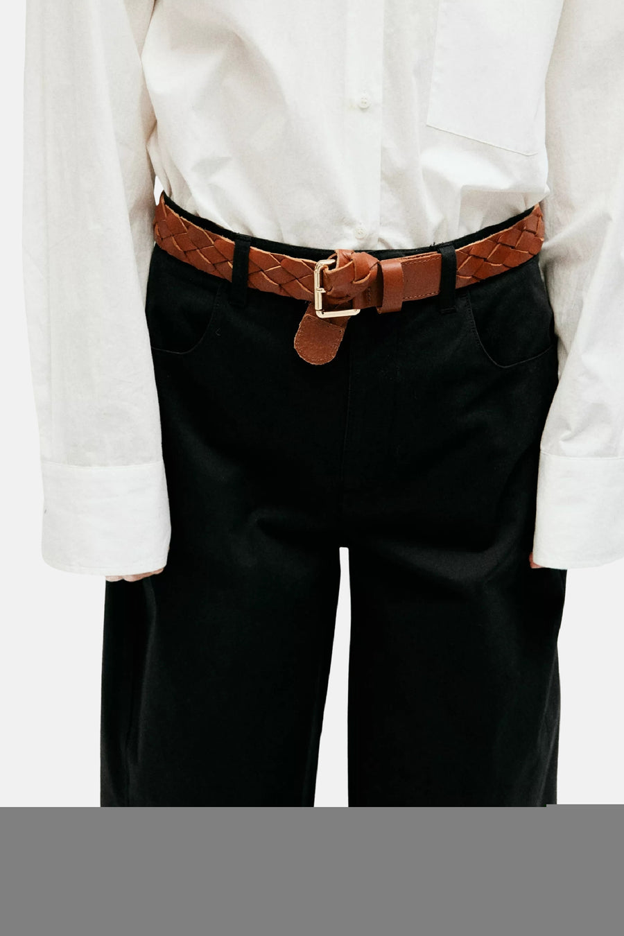 Pantalon cargo noir de MANGO, porté avec chemise blanche et ceinture en cuir tressé marron, vue frontale.