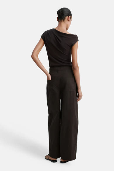Pantalon cargo brun ample par MANGO, vue arrière, poches latérales, tissu structuré, modèle portant top noir et sandales plates