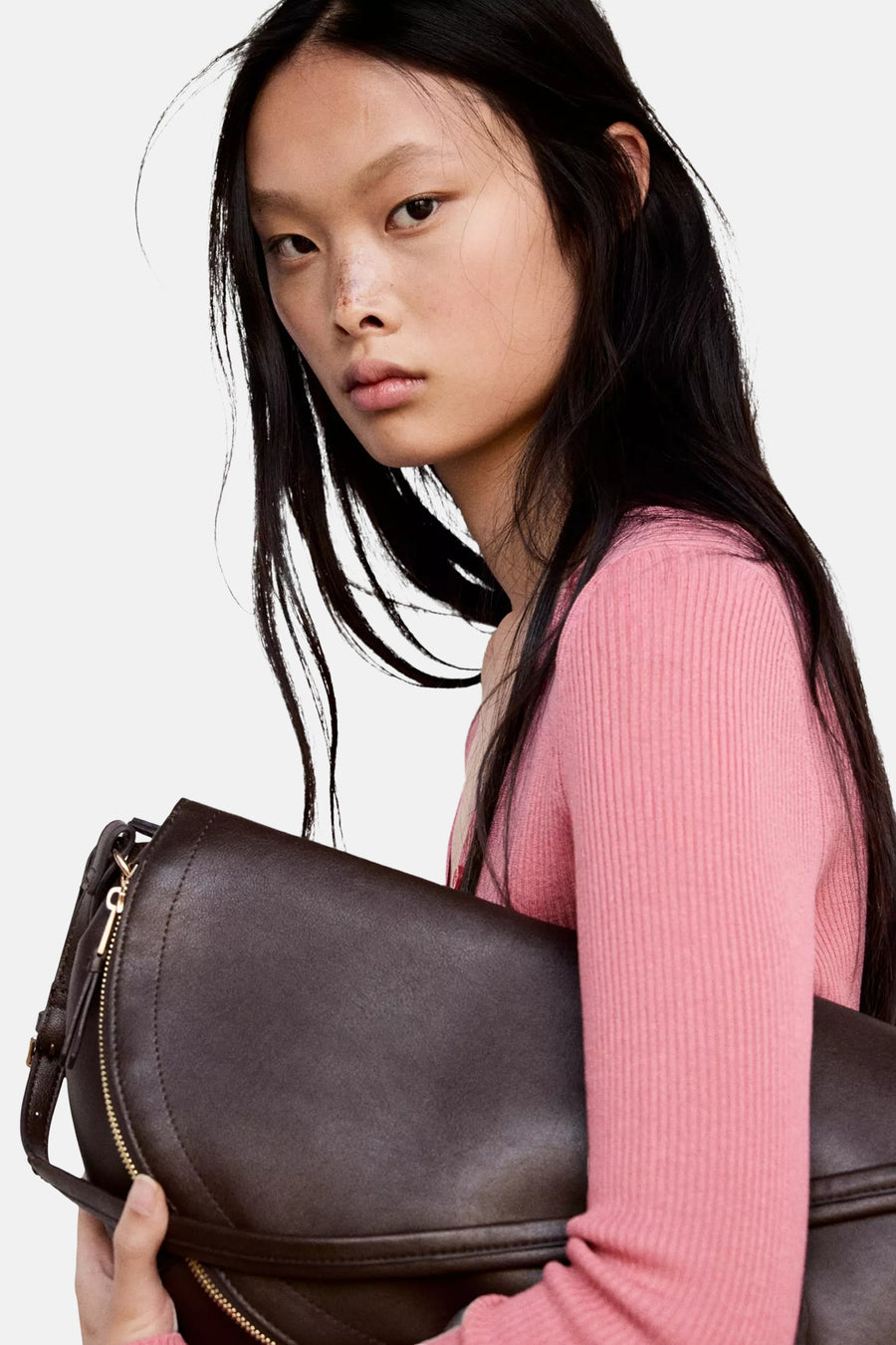 Rose ribbed knit cardigan by [brand omitted] worn in lifestyle side view with dark brown leather bag held close