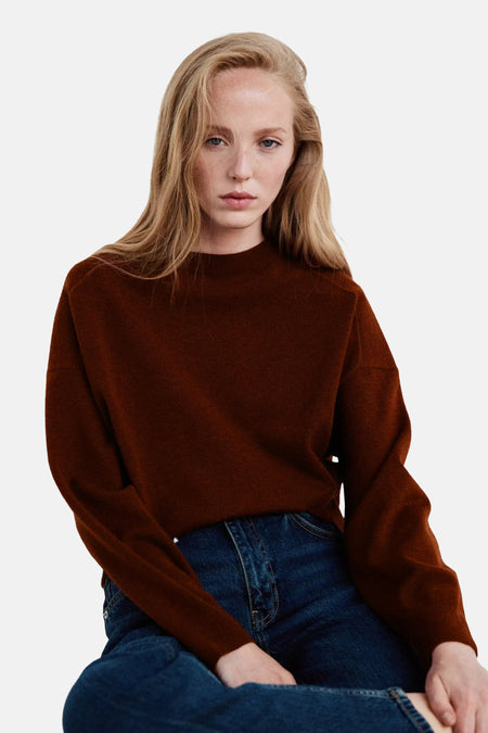 Pull col rond marron par MANGO, en tricot doux, porté avec un jean bleu foncé, vue de face.