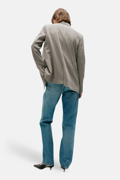 Multicolored houndstooth blazer with structured shoulders, worn back view, paired with blue jeans and black heels