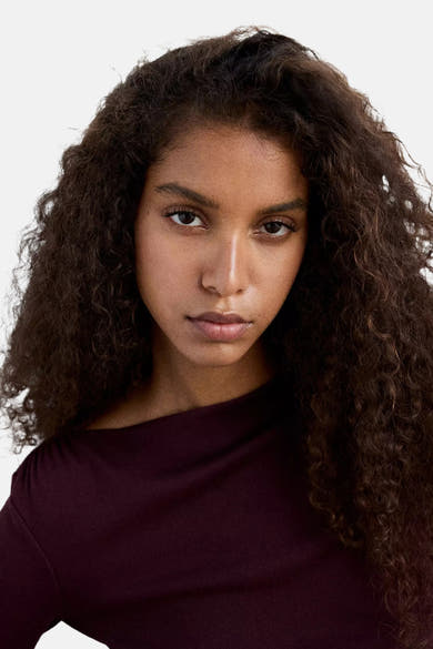 Bordeaux long-sleeve t-shirt with ribbed texture, worn by model with curly hair, front cropped view