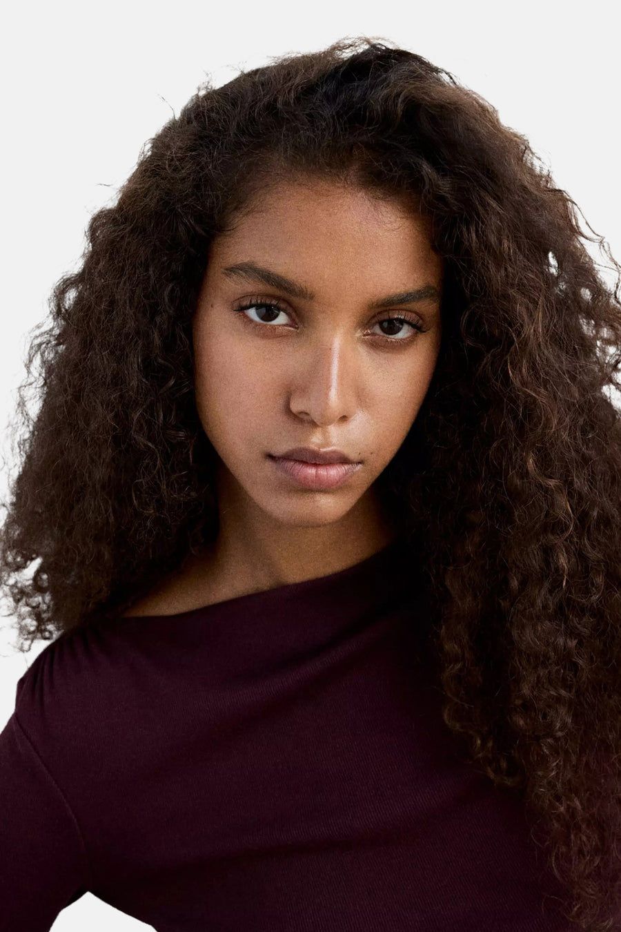 Bordeaux long-sleeve t-shirt with ribbed texture, worn by model with curly hair, front cropped view
