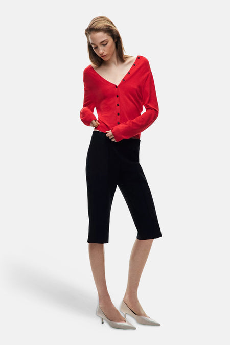 Cardigan rouge à boutons noirs de MANGO, porté avec jupe noire et escarpins clairs, vue de face.