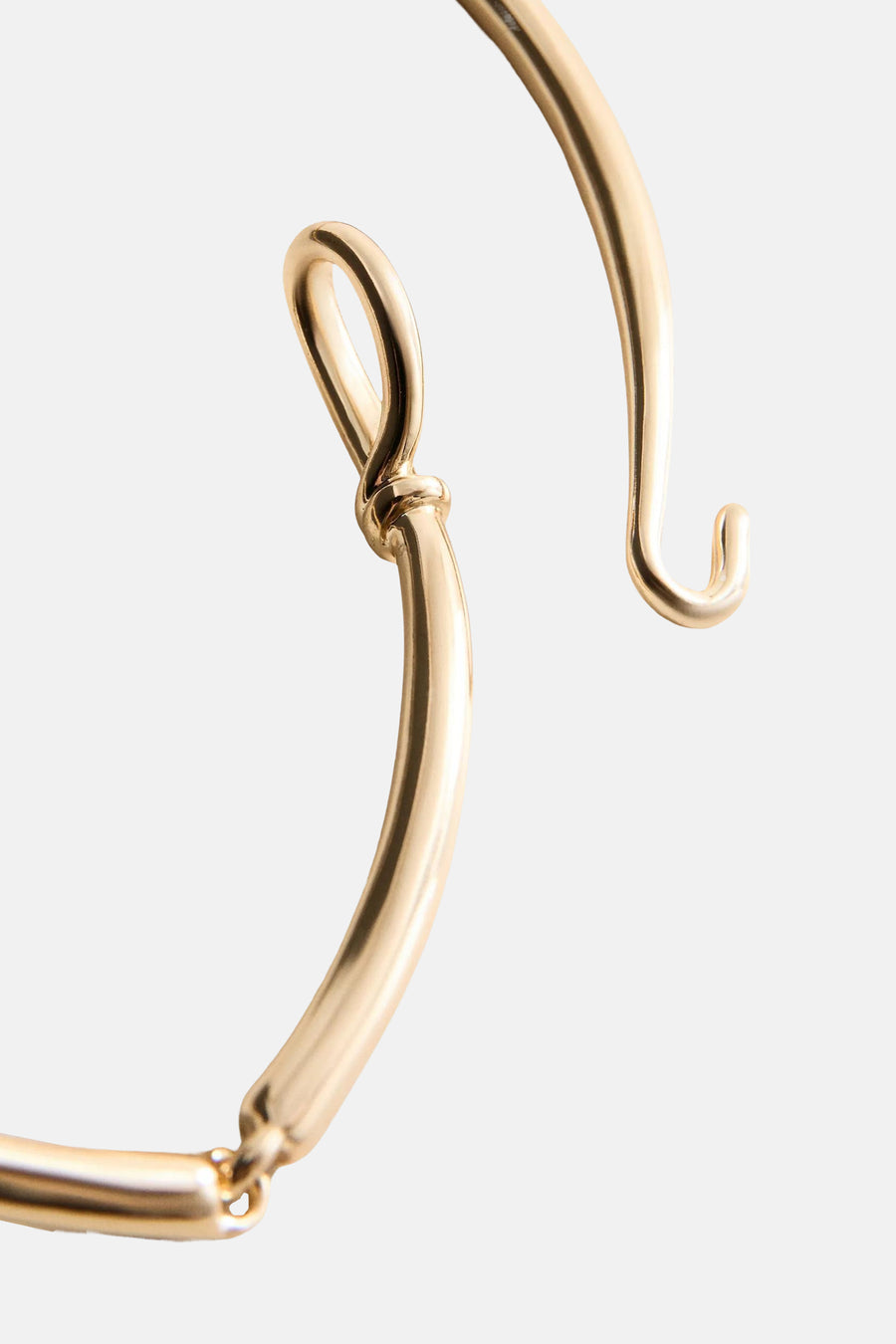 Gold-toned short necklace with sleek curved links and polished finish, close-up side view