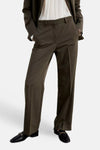 Khaki suit pants with straight-leg cut and front pleats, worn with matching blazer, white shirt, and black loafers with gold hardware, front view