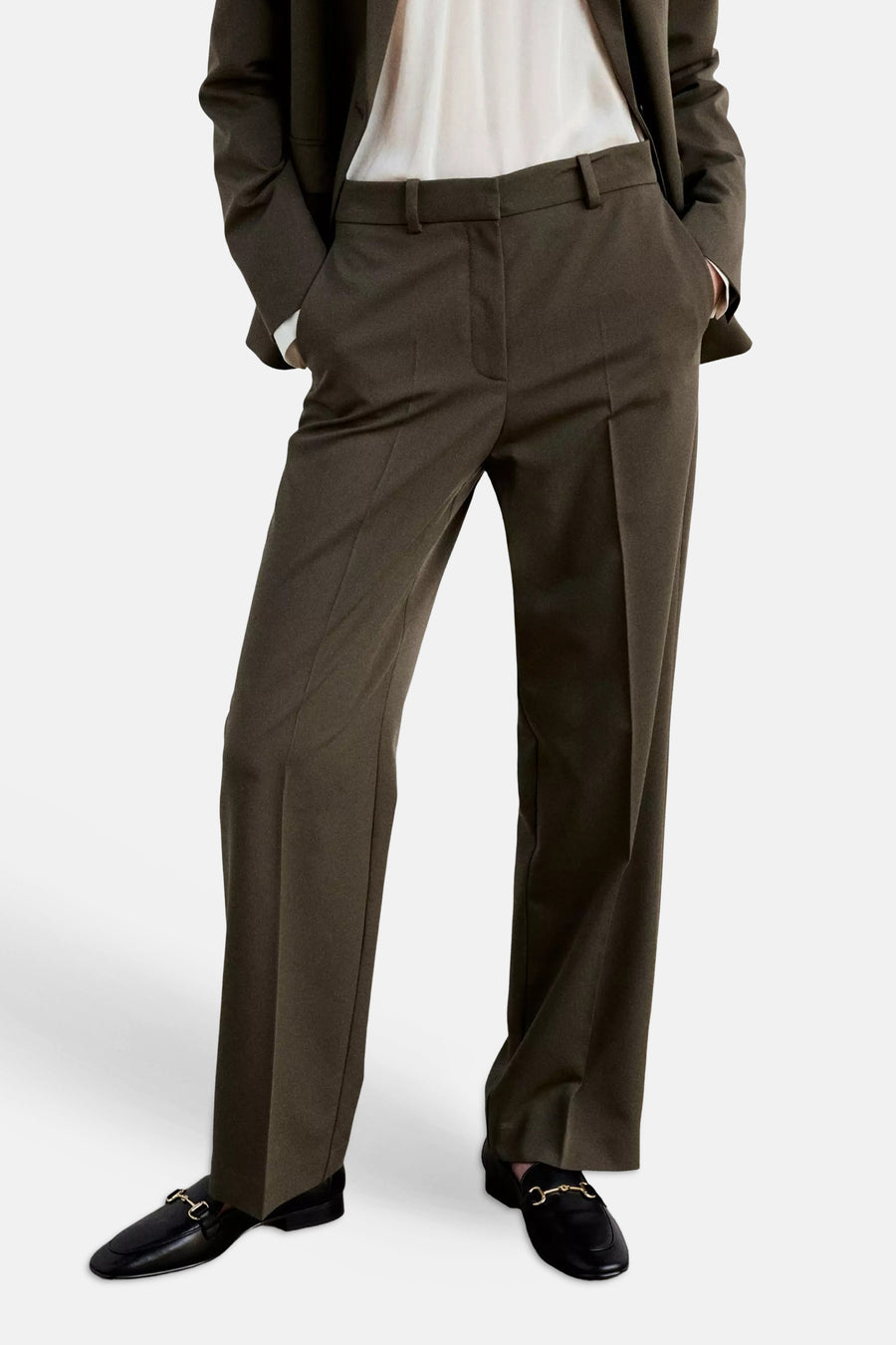 Khaki suit pants with straight-leg cut and front pleats, worn with matching blazer, white shirt, and black loafers with gold hardware, front view