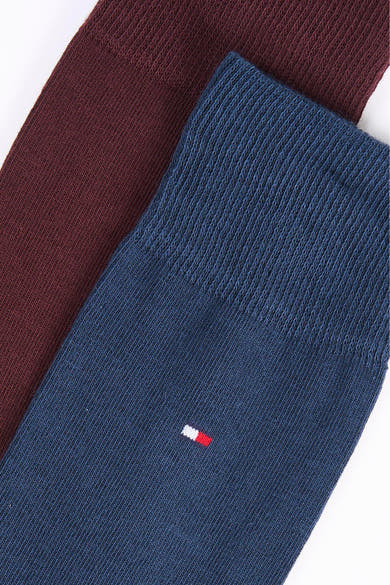 Gros plan sur des chaussettes TOMMY JEANS bleu marine et bordeaux, avec un petit drapeau bicolore.
