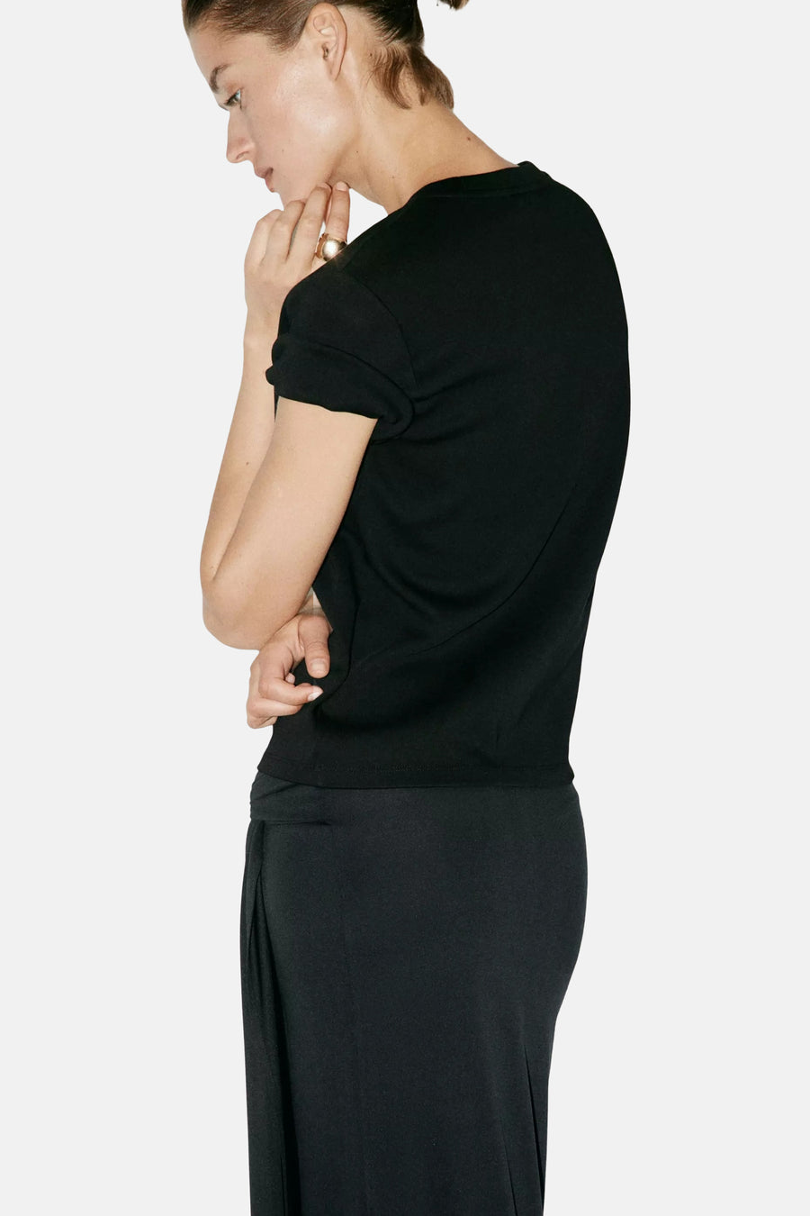 Black short-sleeve t-shirt with ribbed hem and rolled sleeves, side view on model wearing black pants