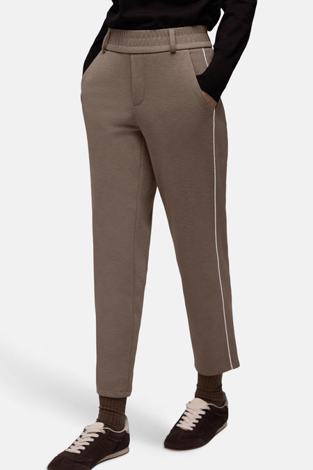 Pantalon beige élastique de STREET ONE avec une bande blanche latérale, porté avec des chaussures de sport marron et des chaussettes côtelées.