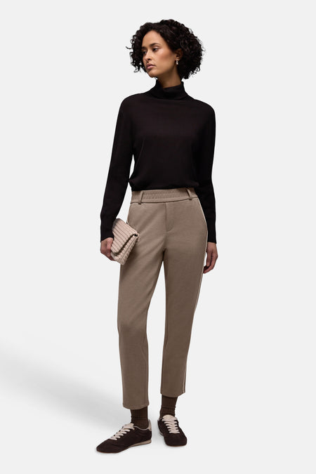 Pantalon beige élastique pour femmes de STREET ONE, avec des baskets marron et un sac à main tressé.
