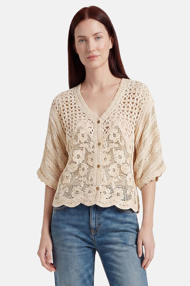Ecru crocheted gilet with floral pattern and scalloped hem, worn over jeans, front view