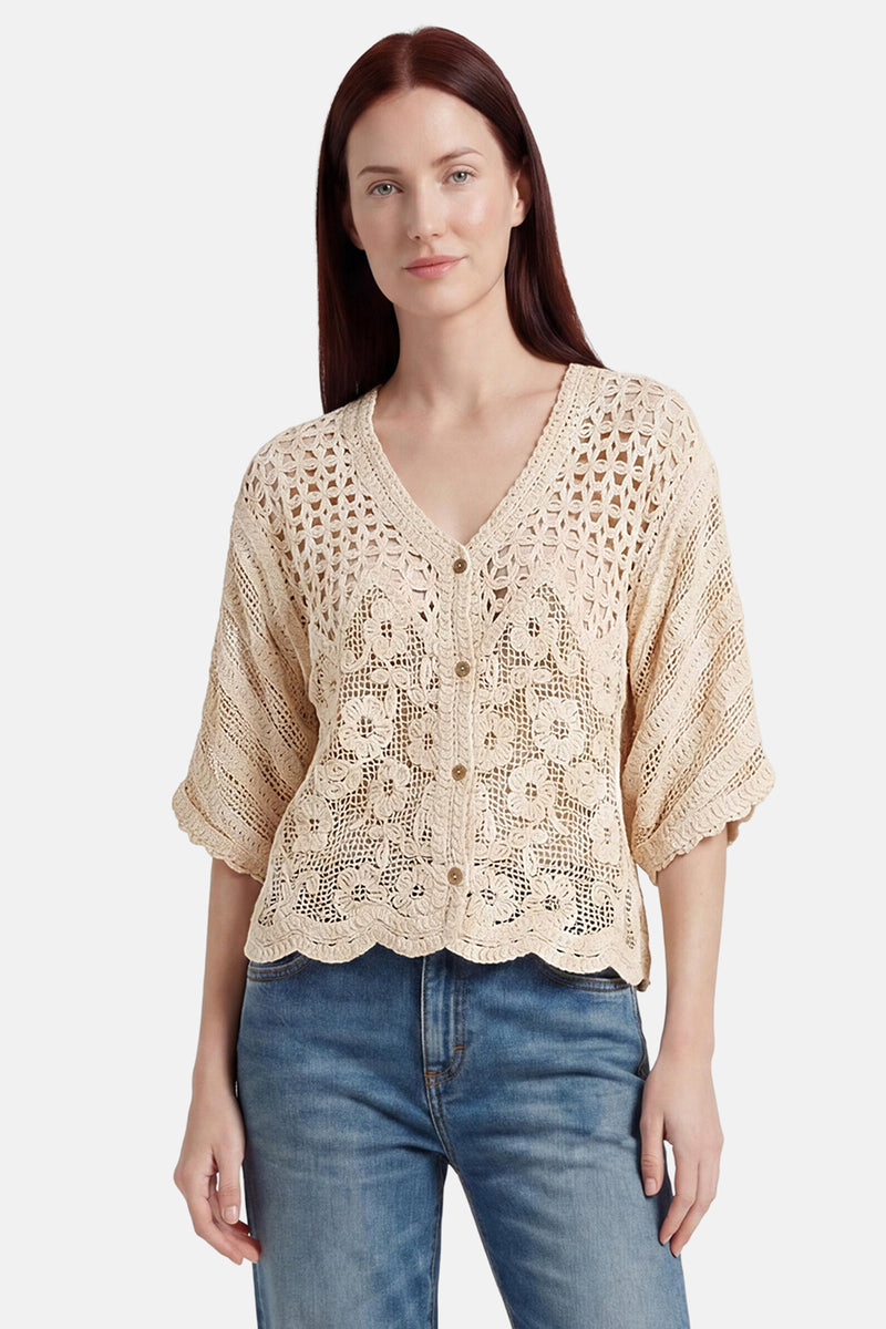 Ecru crocheted gilet with floral pattern and scalloped hem, worn over jeans, front view