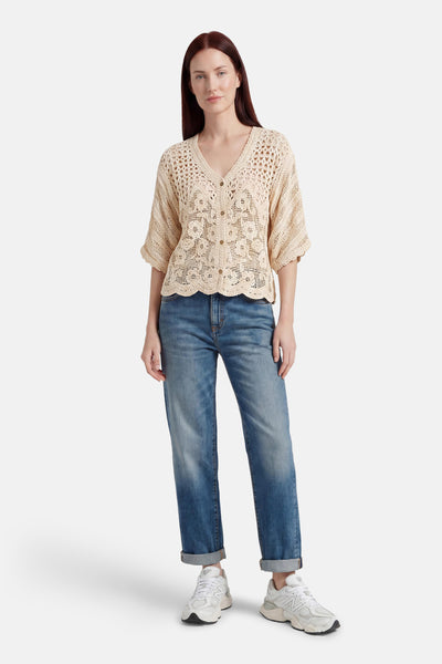 Ecru crocheted gilet with floral pattern and scalloped hem, worn over jeans and sneakers in full-length lifestyle view