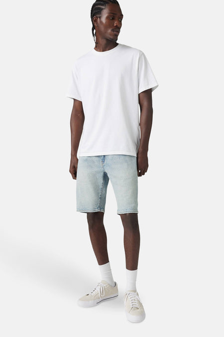 Short en denim bleu clair de Levi's®, porté avec un t-shirt blanc, des chaussettes blanches et des baskets claires.
