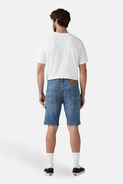 Korte spijkerbroek in middinblauw van Levi's, gedragen met een wit T-shirt en zwarte casual schoenen.