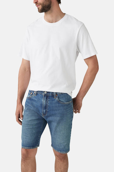 Korte spijkerbroek in middinblauw van Levi's®, gedragen met een effen wit T-shirt.