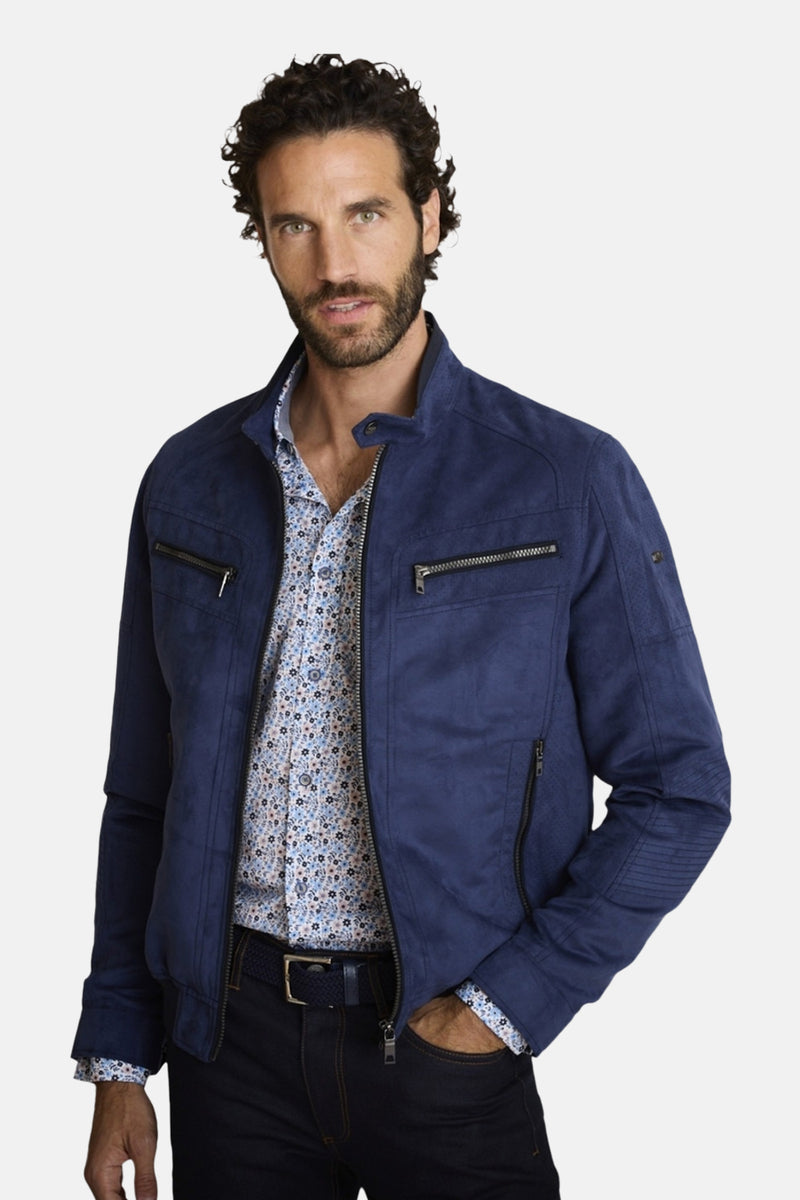 Veste courte bleu marine en suédine de DELAHAYE, avec poches zippées, portée sur une chemise à motifs floraux.