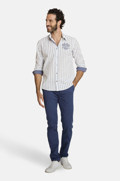 Multikleuren gestreept overhemd van DELAHAYE, met opgerolde mouwen, gedragen met een blauwe broek en witte sportschoenen.