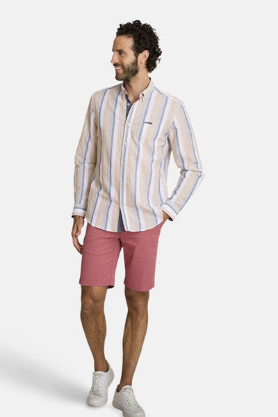 Chemise à manches longues beige rayée, de DELAHAYE, portée avec un short rouge et des chaussures blanches.