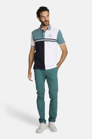 Polo multicolore de DELAHAYE avec empiècements contrastés et manches courtes, porté avec un pantalon vert et des baskets blanches.