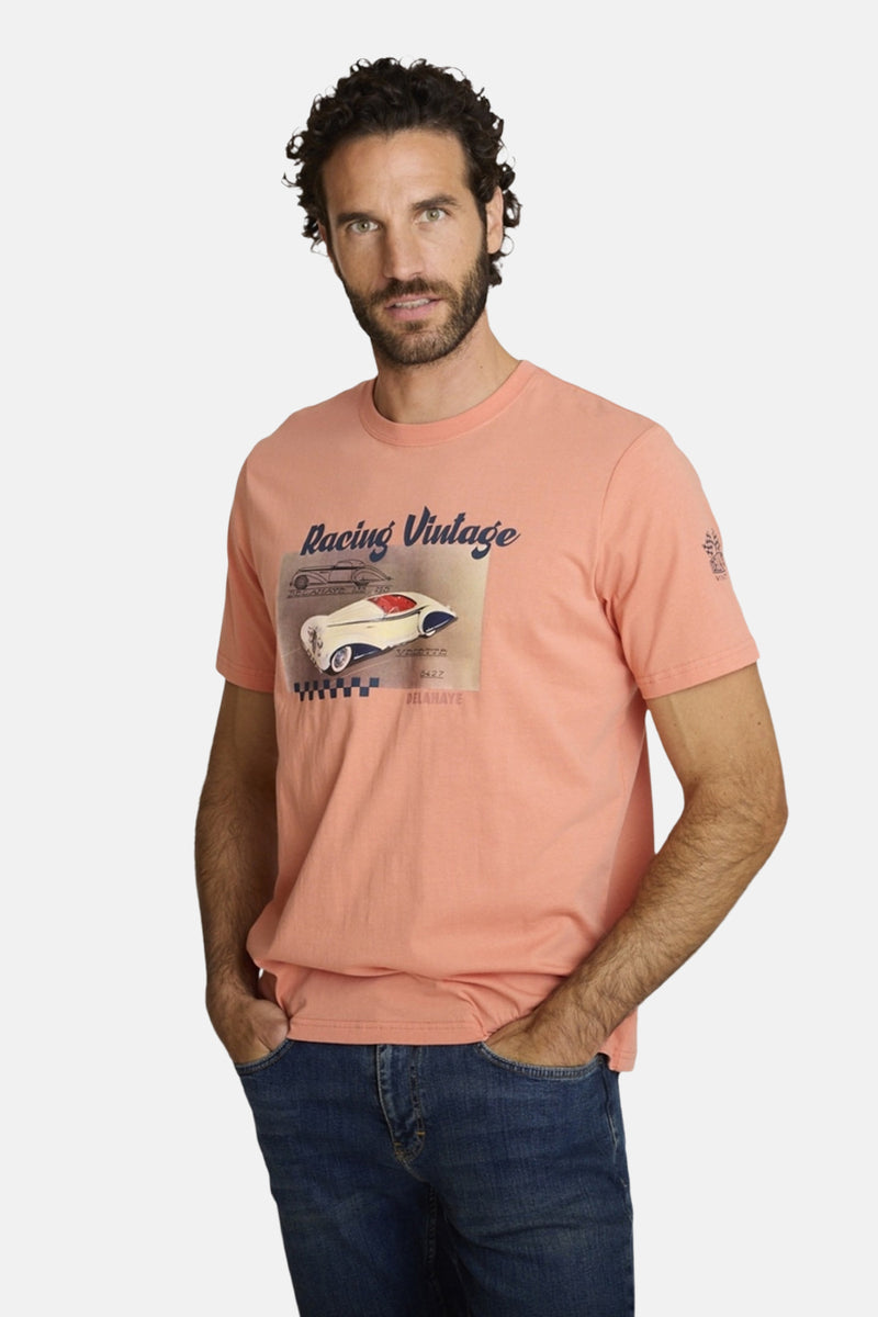 Orange polo shirt with vintage racing car graphic, worn by model in front view, paired with blue jeans