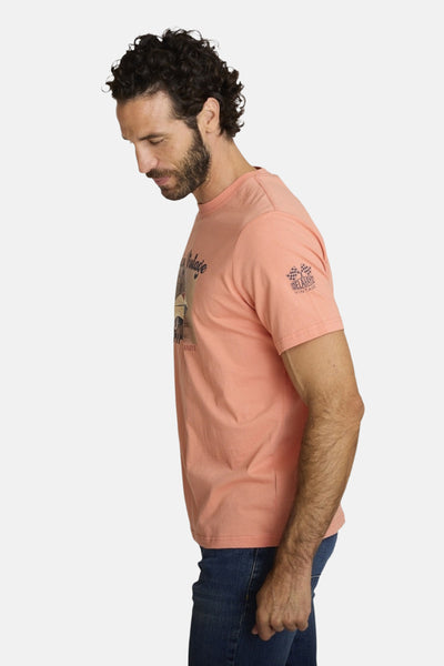 Orange polo shirt with vintage graphic and checkered logo on sleeve, side view of model wearing jeans