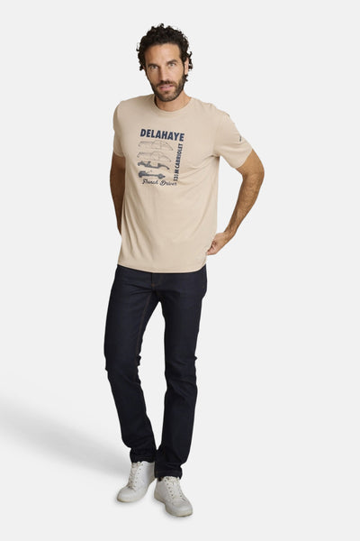 Beige polo shirt with vintage car graphic and text, worn by model in full-length lifestyle pose with dark jeans and white sneakers