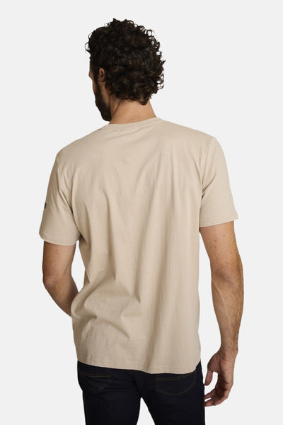 Beige polo shirt back view, soft cotton texture, short sleeves, small logo on left sleeve, worn with dark jeans