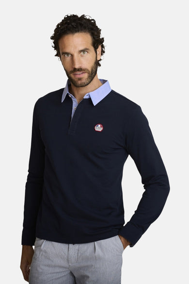 Donkerblauwe DELAHAYE polo met lange mouwen, driekleurige bies en rugpand, gedragen met een gestreepte broek.