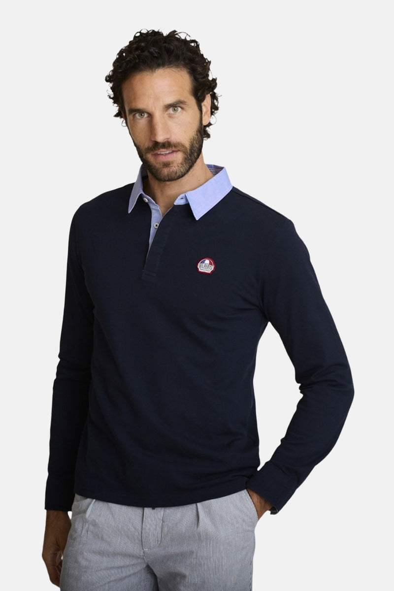 Donkerblauwe DELAHAYE polo met lange mouwen, driekleurige bies en rugpand, gedragen met een gestreepte broek.