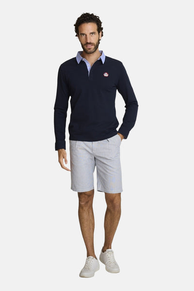 Marineblauwe polo van DELAHAYE met contrasterende lichtblauwe kraag, gedragen met een gestreepte korte broek en witte sneakers.
